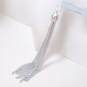 Peut inclure: Un pendentif en cha&icirc;ne argent&eacute;e avec un dessus rond et textur&eacute;. Le pendentif est compos&eacute; de plusieurs brins de cha&icirc;ne.