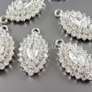 Puede incluir: Encantos de colgante de plata con un gran strass de forma marquesa transparente rodeado de strass transparentes m&aacute;s peque&ntilde;os. Los encantos tienen un bucle en la parte superior para sujetar a las joyas.