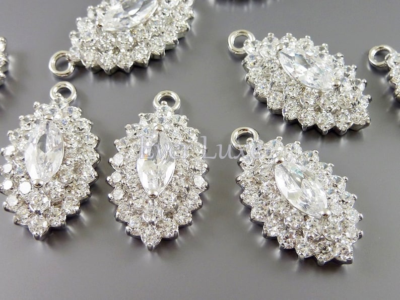 Puede incluir: Encantos de colgante de plata con un gran strass de forma marquesa transparente rodeado de strass transparentes m&aacute;s peque&ntilde;os. Los encantos tienen un bucle en la parte superior para sujetar a las joyas.