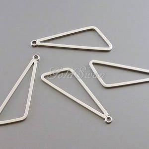 May include: Four silver triangle shaped metal charms with jump rings. The charms are all different sizes and shapes.