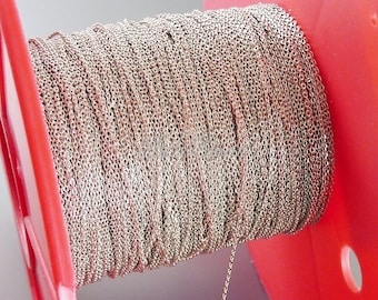 May include: A spool of silver chain, wound tightly around a red plastic spool. The chain is a delicate, fine-link style.