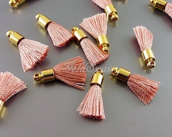 May include: A group of 10 pink tassel charms with gold metal caps. The tassels are made of soft, fluffy yarn and are perfect for adding a touch of elegance to any project.