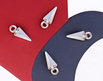 May include: Four silver-colored, cone-shaped charms with a loop at the top. The charms are scattered on a background of red, navy blue, and white. These charms are suitable for jewelry making.
