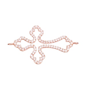 May include: A rose gold cross pendant encrusted with sparkling clear crystals. The cross features an openwork design with rounded edges and small loops at the ends for attaching to a chain or other jewelry. The pendant is set against a white background.