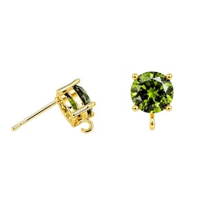 Puede incluir: Un par de pendientes de botón en tono dorado con piedras redondas de color verde oliva talladas. Cada engaste incluye un pequeño lazo circular en la base para añadir componentes de joyería adicionales, con un poste estándar en la parte trasera.