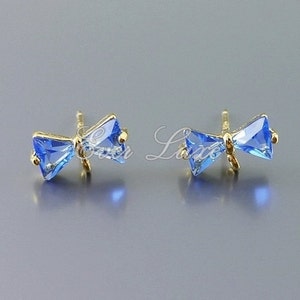 May include: A pair of gold bow earrings with blue crystal accents.
