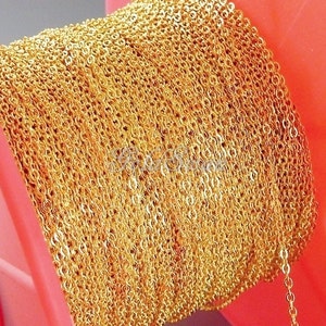 May include: A spool of gold-colored chain, wound tightly around a red plastic spool. The chain is made of small, linked circles.