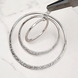 May include: Silver hoop earrings with a textured finish. The earrings feature three interlocking circles.