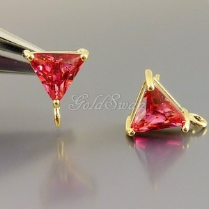 May include: Two gold-tone triangle-shaped earring charms with a pink crystal in the center. Each charm has a loop at the bottom for attaching to a chain or other jewelry.