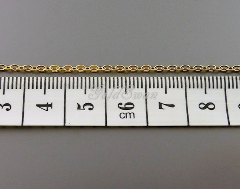 May include: A gold chain measuring 6 cm in length, laid out on a white measuring tape.