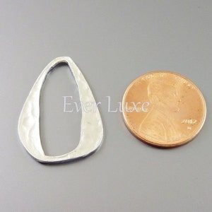 Pu&ograve; includere: Un ciondolo in metallo argentato martellato a forma di lacrima con una grande apertura ovale. Il ciondolo &egrave; circa delle dimensioni di una moneta da un centesimo di euro.