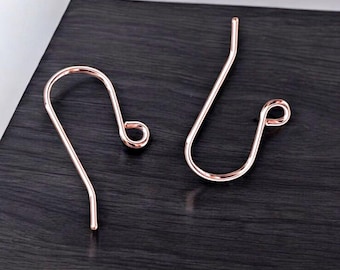 May include: Two rose gold earring hooks. The hooks are made of metal and have a simple, elegant design.