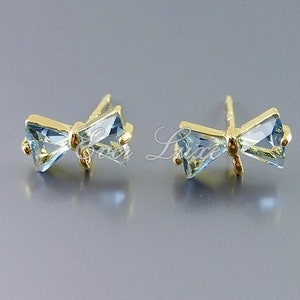 May include: A pair of gold bow-shaped earrings with light blue gemstone accents.