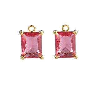 May include: A pair of gold-tone earring charms with square-shaped pink glass stones.