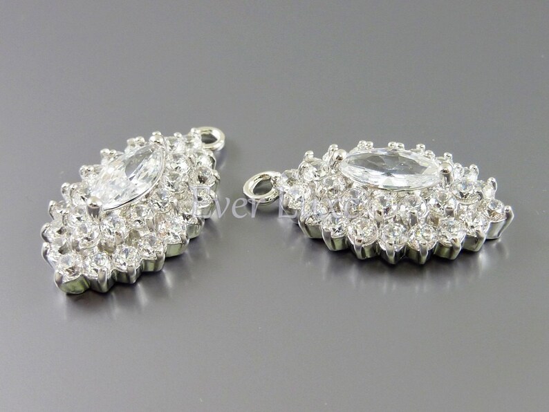 Puede incluir: Dos colgantes de plata con un gran cristal de imitaci&oacute;n transparente en forma de marquesa rodeado de cristales de imitaci&oacute;n transparentes m&aacute;s peque&ntilde;os.