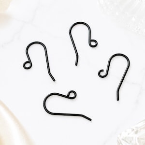 May include: Four black metal earring hooks, each featuring a curved wire design with a small circular loop at the top for attaching jewelry components. These earring findings have a smooth, matte black finish and a simple, functional shape.