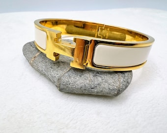 Bracciale Hermès Clic H in smalto bianco placcato oro, prodotto in Francia.
