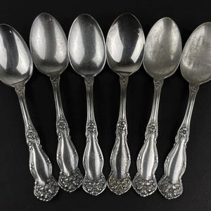 May include: Set of six silver spoons with ornate handles. The spoons have a polished finish and are in excellent condition.