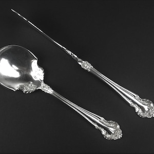 May include: A set of two silver-plated serving utensils, a spoon and a knife, with ornate handles.