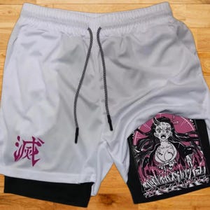 May include: White athletic shorts with a black waistband and a pink Japanese character on the left leg. The shorts have a black inner layer with a graphic print of a female anime character with pink and black accents.