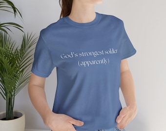May include: A blue t-shirt with the text "God's strongest soldier (apparently)" printed in white.