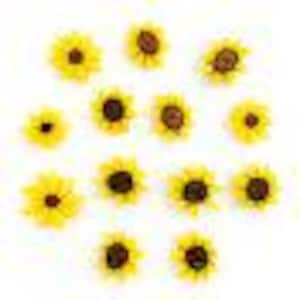 Puede incluir: Una colección de pequeños girasoles artificiales amarillos con centros marrones, dispersos sobre un fondo blanco. Las flores están en varias etapas de floración, con arreglos detallados de pétalos.