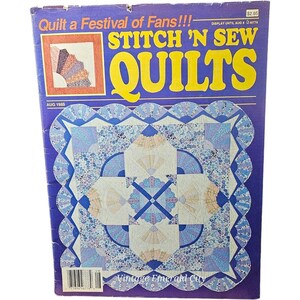 May include: A vintage Stitch 'N Sew Quilts magazine cover from August 1989 featuring a quilt with a blue, white, and pink floral pattern. The quilt is made up of a series of fans, and the magazine cover text reads "Quilt a Festival of Fans!!!".