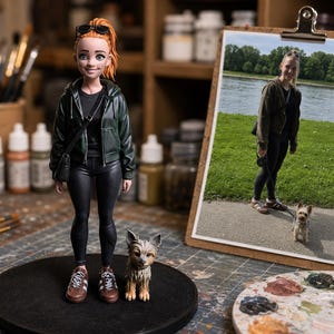 Może przedstawiać: Personalizowana figurka osoby z pomarańczowymi włosami w kucyku, ubrana w ciemnozieloną bluzę z kapturem na zamek, czarną koszulkę, czarne legginsy i brązowe buty sportowe, stojąca obok małego brązowo-czarnego psa na czarnej podstawie.