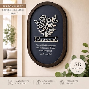 May include: A dark wood-framed oval sign with a navy blue background. The sign features a 3D floral design and the word "Blessed" in a cursive font. Below, a Bible verse is inscribed. The sign is labeled "Personalized Custom Bible Verse."