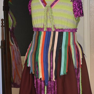 May include: A green and purple dress with a striped bodice and a skirt made of colorful zippers. The dress has a ruffled hem and a green hat.