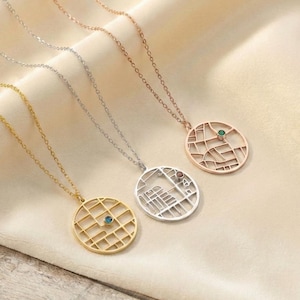 Peut inclure: Quatre colliers avec des pendentifs en forme de carte. Les colliers sont en or, argent et or rose. Chaque pendentif a une pierre précieuse de couleur différente. Les colliers sont présentés sur un tissu crème.