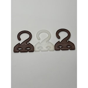 May include: Three plastic garment hangers. Two are brown, and one is white. Each hanger has a curved hook and a lower section with three small, rounded protrusions. The text "JUPPER WARE" is printed on the brown hangers.