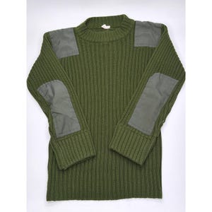 Puede incluir: Jersey de punto acanalado verde oliva con parches reforzados en hombros y codos. El jersey tiene cuello redondo y mangas largas. Una prenda clásica y duradera.