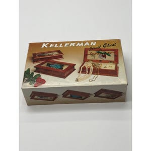 Könnte beinhalten: Eine Vintage-Kellerman-Schmuckkasten-Box. Die Box zeigt Bilder von hölzernen Schmuckkästchen mit floralen Designs und geöffneten Boxen mit Schmuck. Die Box ist braun und weiß mit dem Text "Kellerman Jewel Chest".