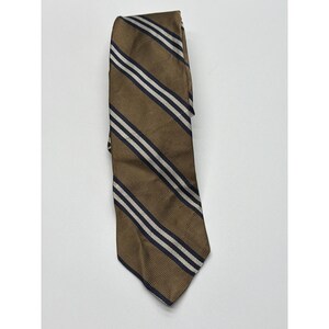 Peut inclure: Une cravate marron avec des rayures diagonales blanches et bleu marine. La cravate est faite d'un tissu texturé et est pliée sur elle-même. Un accessoire classique pour les tenues formelles ou professionnelles.