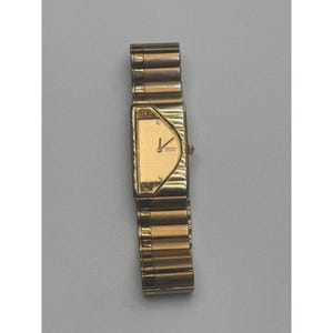 May include: A gold-toned Seiko watch with a rectangular face and a matching link band. The watch face has a minimalist design with gold hands and hour markers. The watch is a classic style.