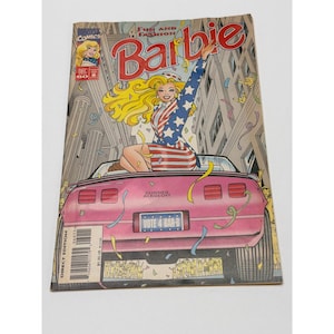 May include: A comic book cover titled "Fun and Fashion Barbie." The cover features a blonde woman in a patriotic outfit, seated in a pink car. The comic is a direct edition and includes the text "Vote 4 Bar-B."