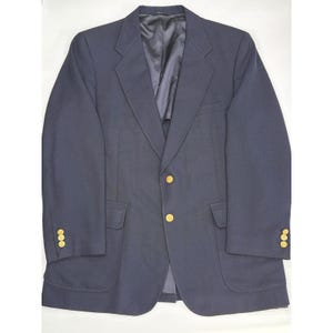 以下が含まれることがあります： 金色のボタンが付いたネイビーブルーのブレザー。 ブレザーには、2つのフロントポケットと各袖口に3つのボタンが付いています。 内側の裏地は濃いネイビー色です。