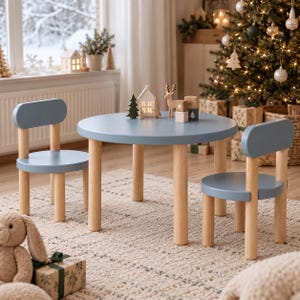 May include: A round, light blue children's table with four cylindrical light wood legs, accompanied by two matching chairs with light blue seats and backrests supported by light wood legs, arranged on a textured, light-colored area rug.