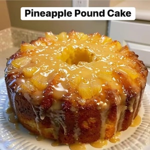 May include: A Pineapple Pound Cake, with pineapple pieces and a sweet glaze. The cake is a golden brown colour and is on a white, decorative plate. The text "Pineapple Pound Cake" is at the top of the image.
