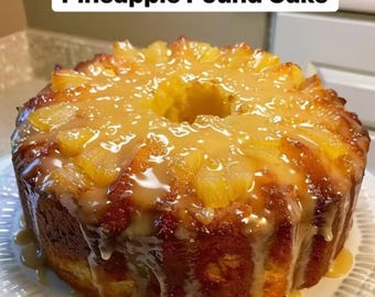 May include: A freshly baked Pineapple Pound Cake, topped with pineapple chunks and a sweet glaze. The cake is golden brown and sits on a white, decorative plate. The text "Pineapple Pound Cake" is at the top of the image.