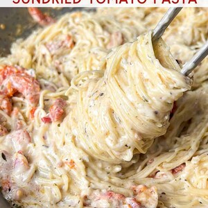 Puede incluir: Primer plano de pasta cremosa con tomates secos en una sart&eacute;n. La pasta se levanta con pinzas, mostrando la salsa y los ingredientes. El texto "ONE-PAN SUNDRIED TOMATO PASTA" se muestra en la parte superior.