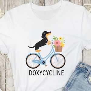Camiseta con juego de palabras sobre farmacia con doxiciclina, perro salchicha en bicicleta, regalos de farmacéutico, camiseta de farmacéutico, camiseta de perro salchicha, regalo divertido para los amantes de los perros salchicha