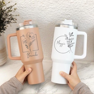 Puede incluir: Dos tazas de viaje personalizadas con diseños florales. La taza de la izquierda es marrón con un diseño floral y el nombre "Brenda". La taza de la derecha es blanca con un diseño floral y el nombre "Maggie".