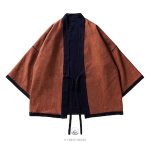 May include: A rust-colored haori jacket with a dark blue denim lining and trim. The jacket has a tie closure at the front and the text "S-CREST HAORI" is printed below the jacket.