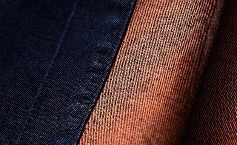 May include: Close-up of two different types of fabric. One is a dark blue denim and the other is a brown denim.