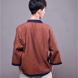 May include: A rust-colored, lightweight jacket with a blue trim. The jacket has a relaxed fit and a slightly cropped hem.