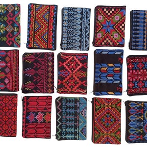 May include: A collection of small, rectangular wallets with intricate embroidered patterns. The wallets feature a variety of colors, including red, blue, and black, with geometric and floral designs. Each wallet has a zipper closure.