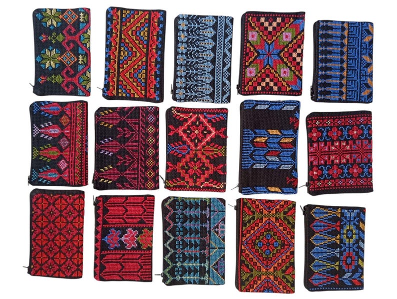 May include: A collection of small, rectangular wallets with intricate embroidered patterns. The wallets feature a variety of colors, including red, blue, and black, with geometric and floral designs. Each wallet has a zipper closure.