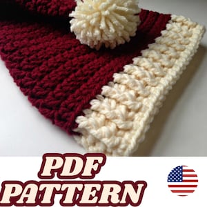 May include: A burgundy and cream-coloured crochet hat. The hat has a textured stitch pattern and a cream-coloured pom-pom. The image includes the text "PDF PATTERN" and a small American flag at the bottom.